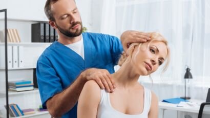 portrait of chiropractor stretching neck of woman during appointment in hospital