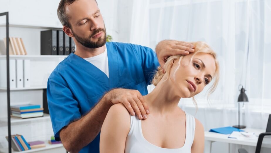 portrait of chiropractor stretching neck of woman during appointment in hospital